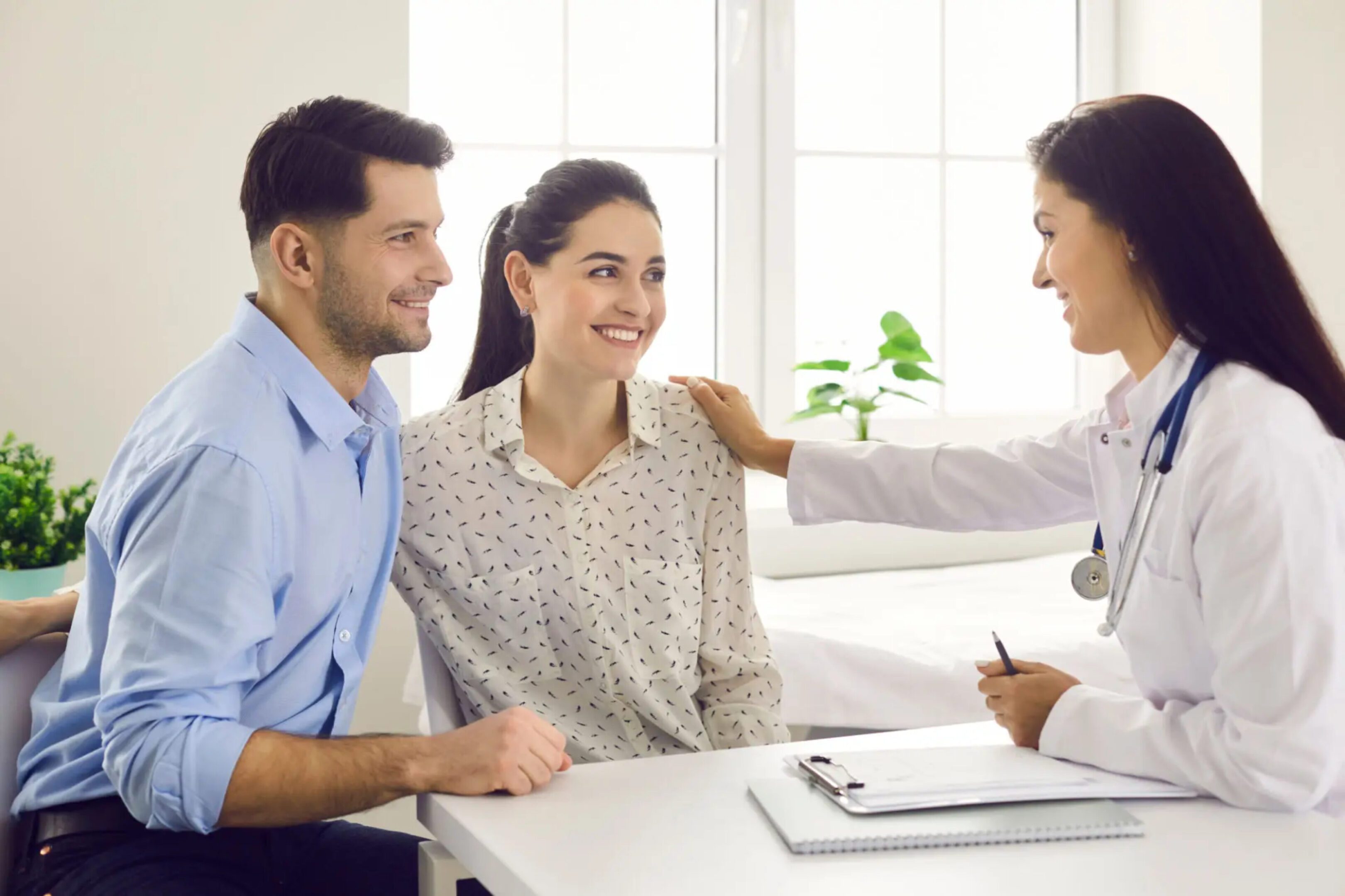 Couple consulting with a female doctor in a bright office.